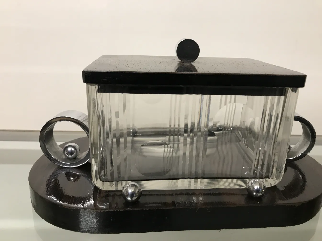 Antike Glasbox mit schwarzem Deckel und runden Details.