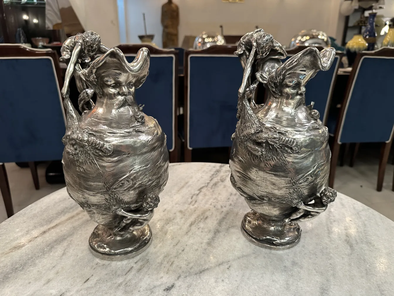 Ensemble de deux pichets anciens avec des décorations complexes, posés sur une table en marbre.