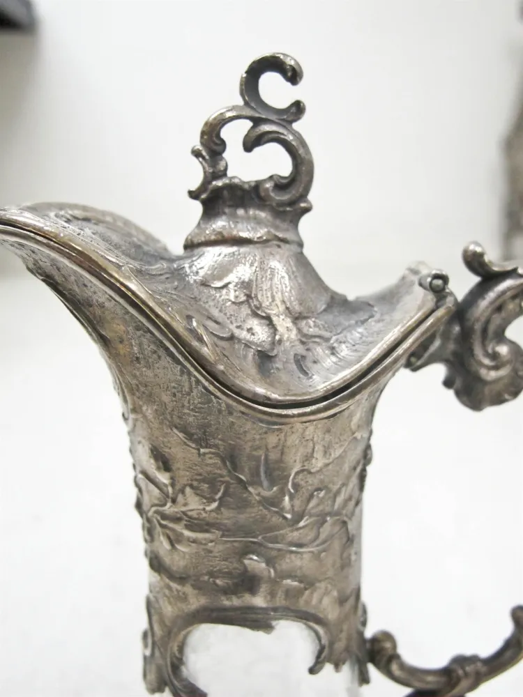 zwei antike WMF Krüge mit komplexem Design und dekorativen Griffen in einem eleganten Ambiente