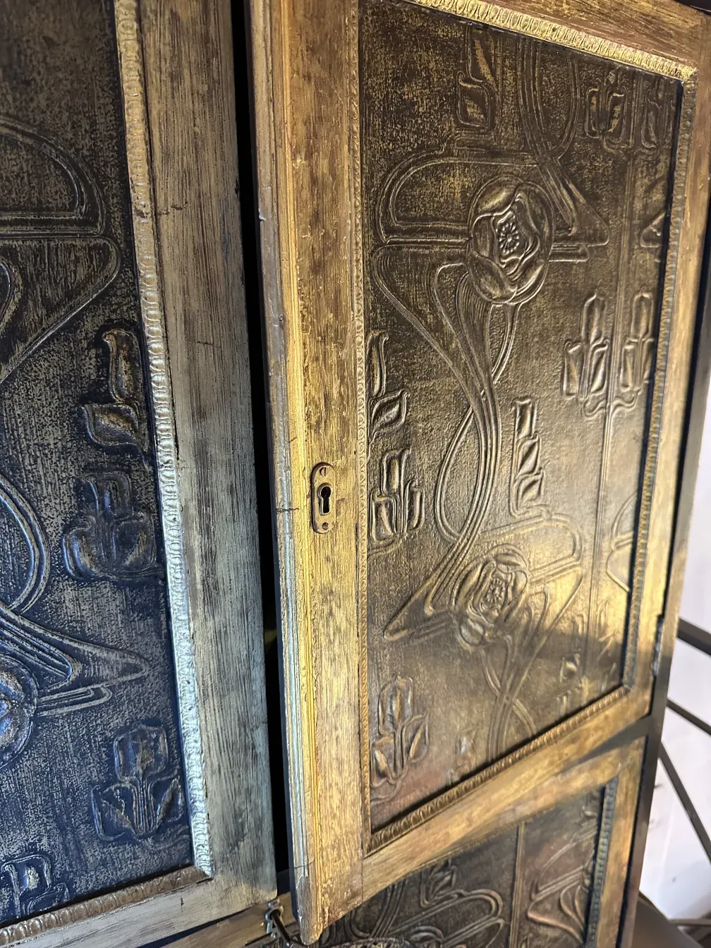 Antique bar cabinet with golden floral reliefs on the surface.