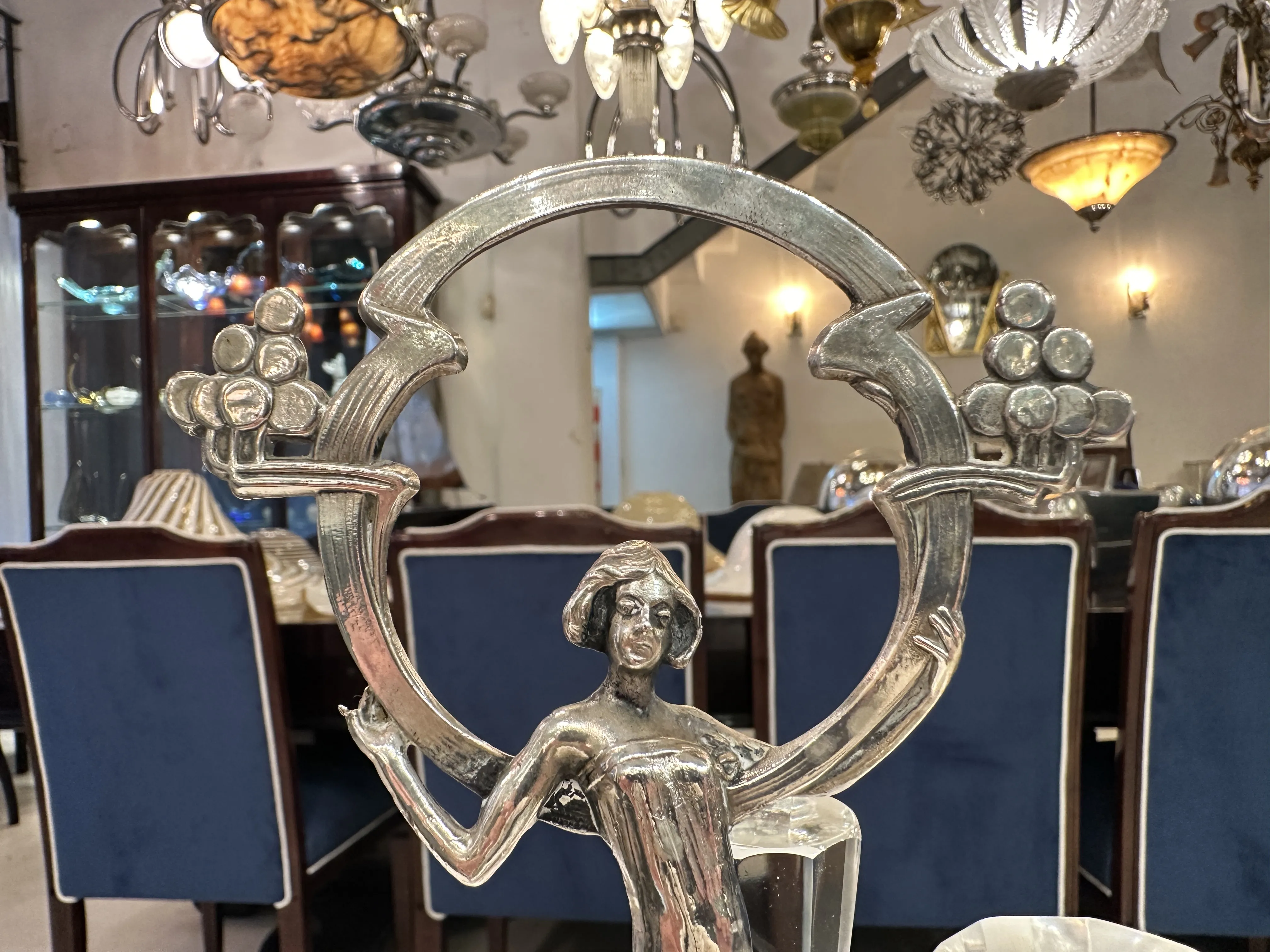 View of an antique salt and pepper shaker with a female figure, set on an elegant table.