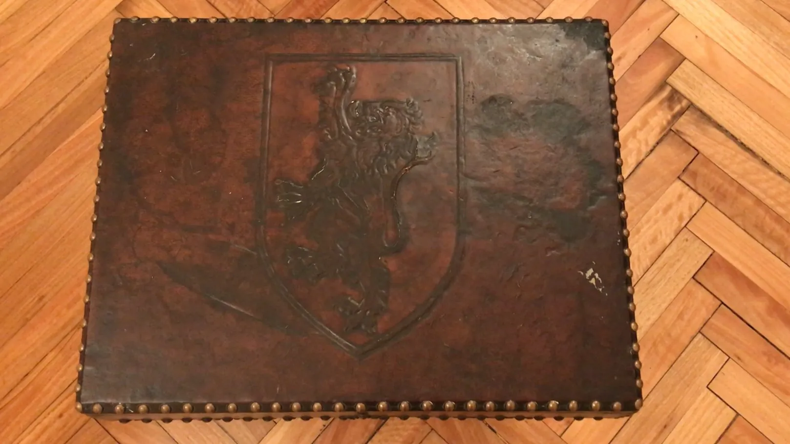 प्राचीन बार कैबिनेट, जिसमें उभरा हुआ शेर और सजावटी कीलें हैं।