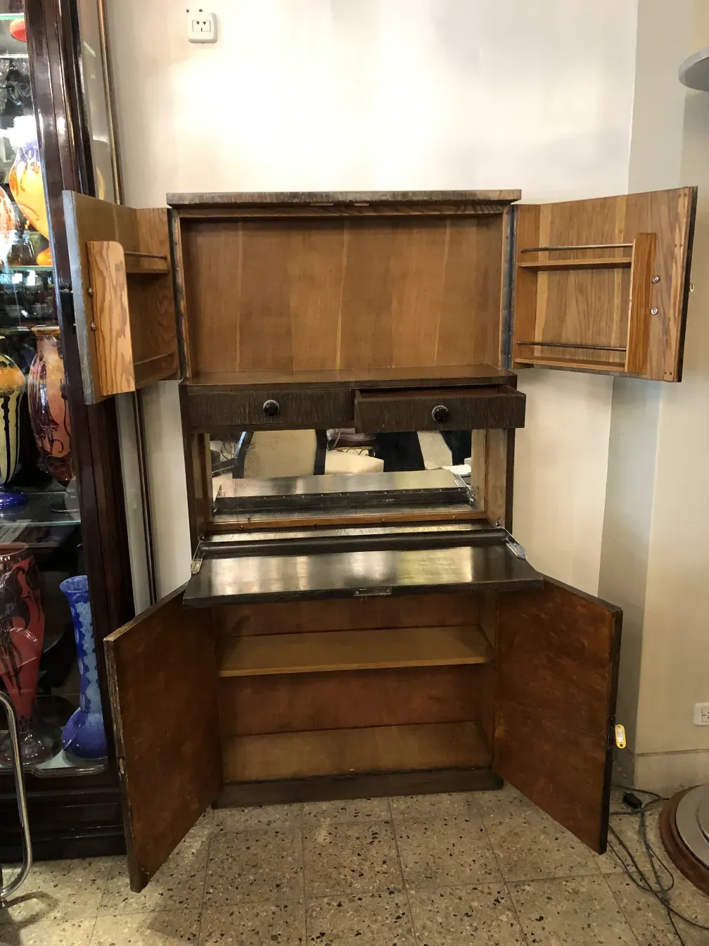 Antiker Cocktailschrank mit Spiegel und zwei Holzschubladen in einem eleganten Ambiente.