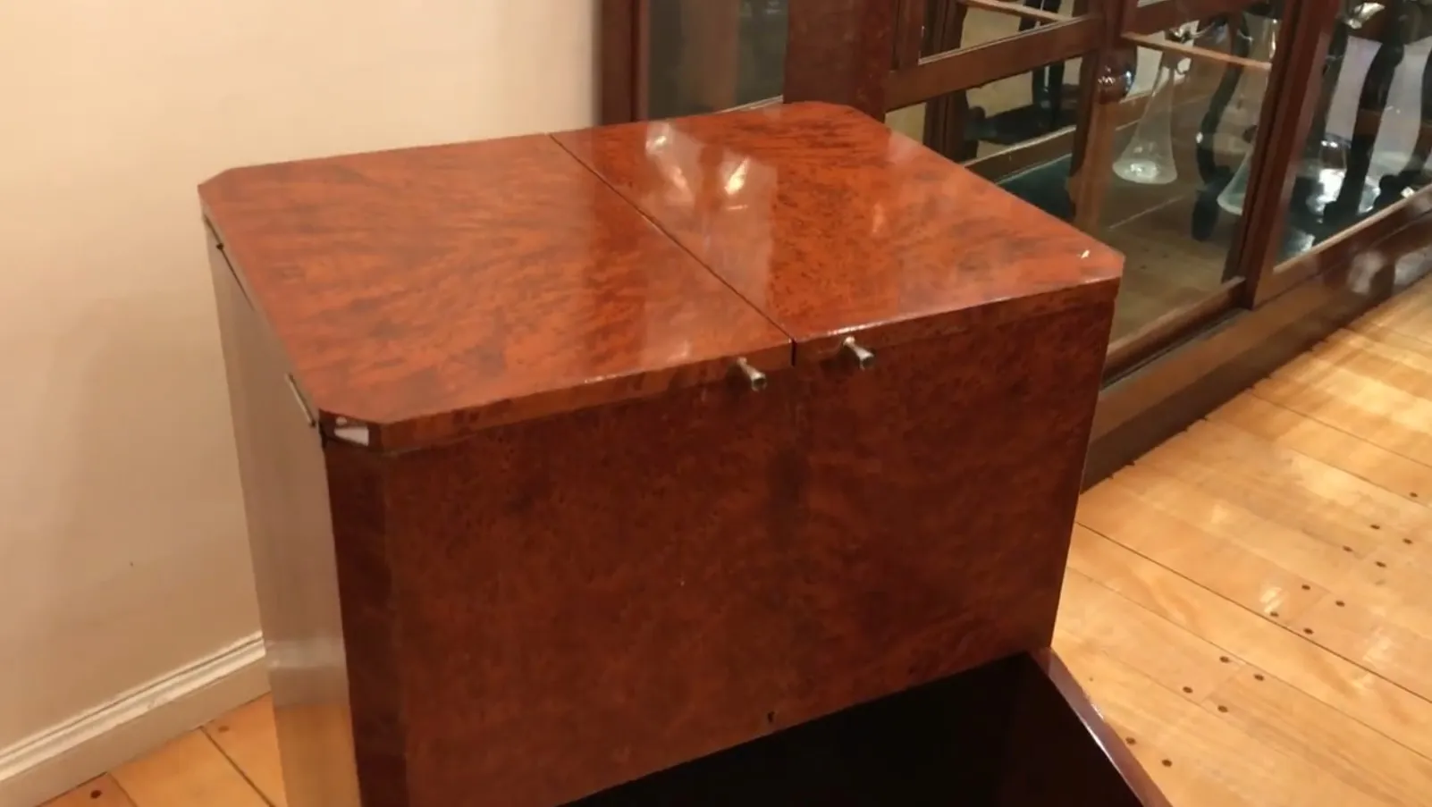 Meuble à cocktail ancien en bois avec finition brillante, dans un cadre accueillant.