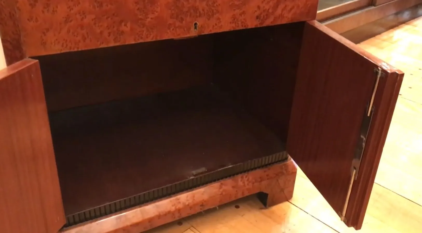 Mueble bar antiguo con puertas abiertas y fondo oscuro