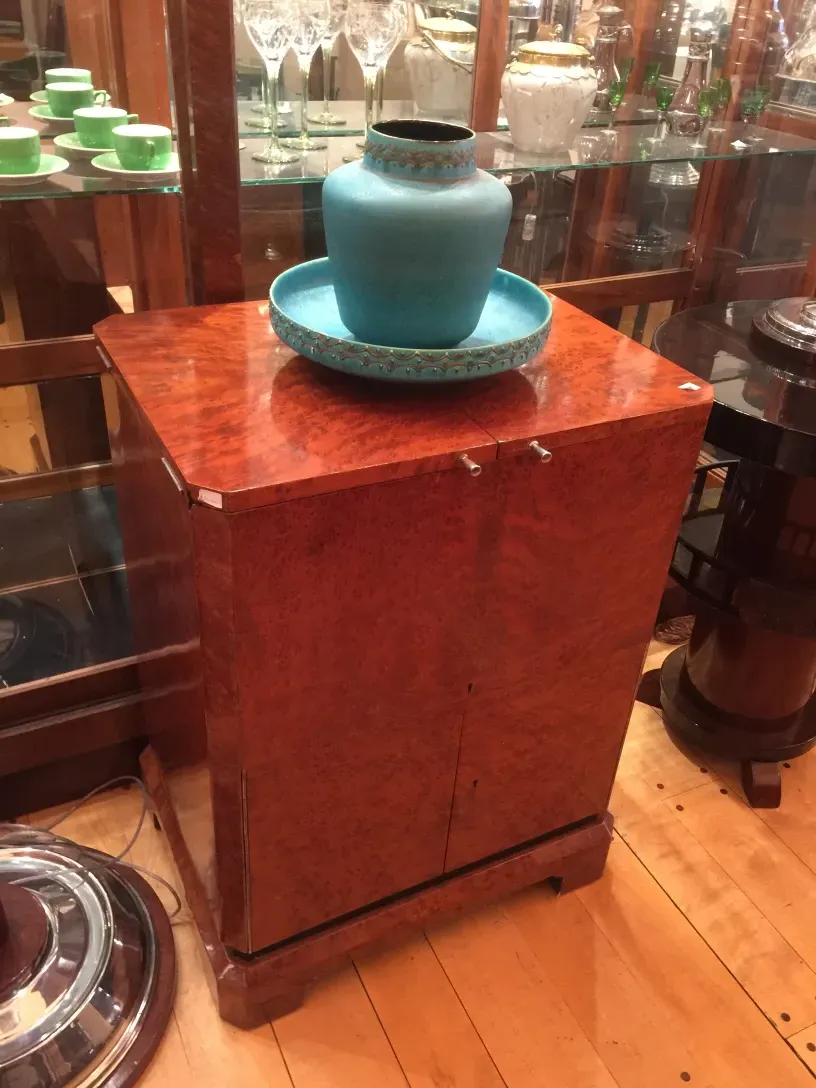 Mueble bar antiguo con superficie brillante y decoración azul.