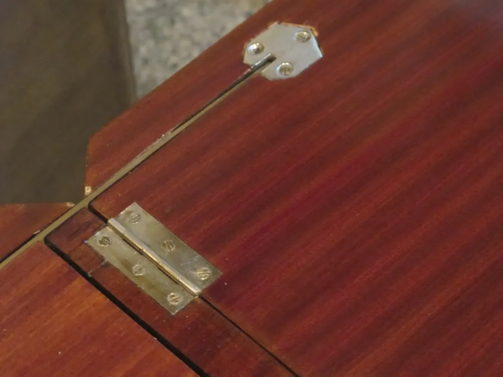 Détail d'un meuble à cocktail ancien avec charnières en métal.