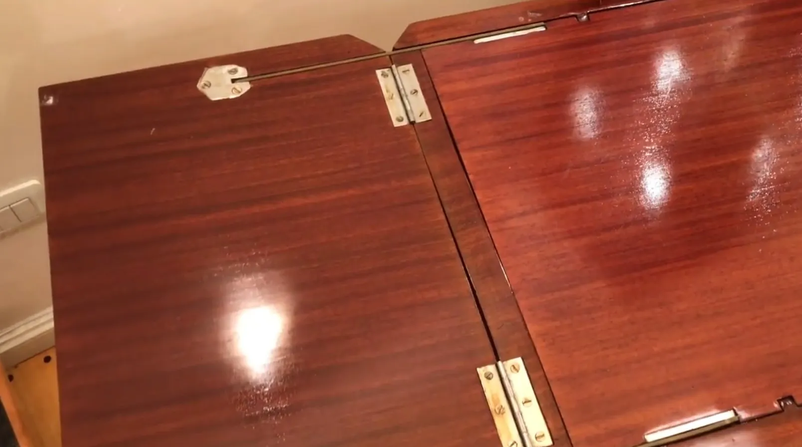 Meuble à cocktail ancien avec une finition lisse et des charnières en métal, exposé dans un cadre chaleureux.