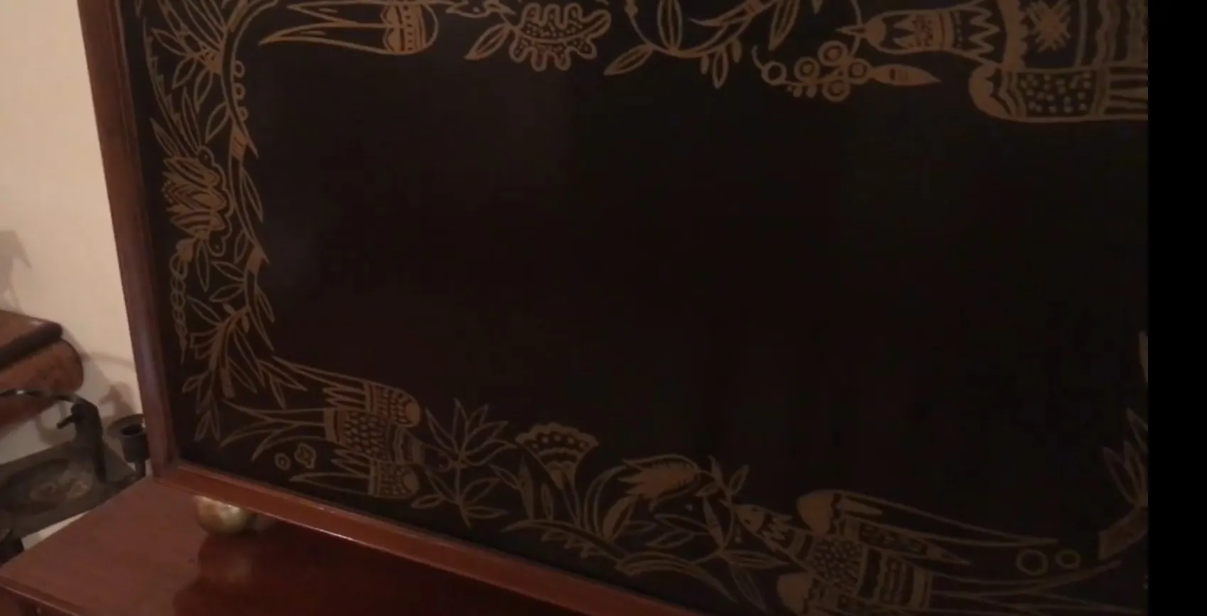 Mueble bar antiguo con decoración floral en fondo oscuro.