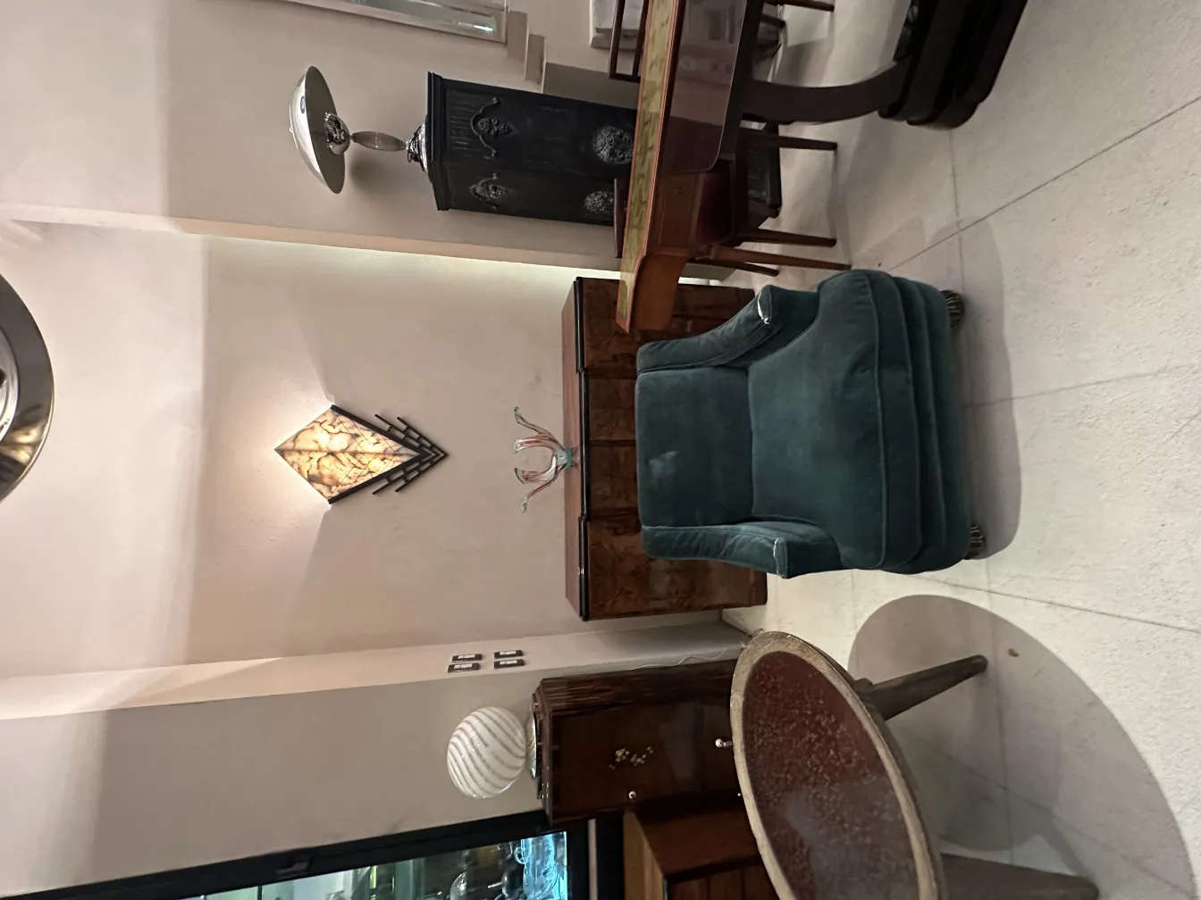 Antica coppia di applique con design elegante e distintivo, che illumina l'ambiente. Include mobili in legno e una poltrona verde.