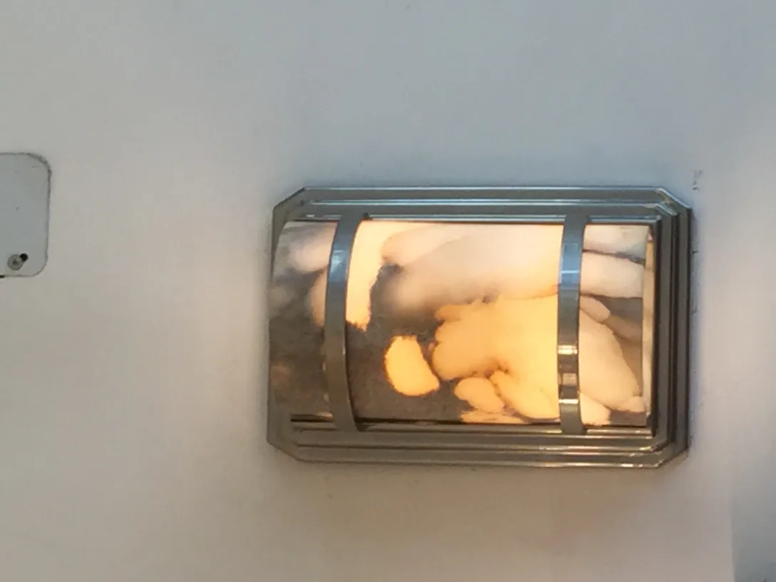 一对古董壁灯，温暖的光线在白色墙面上。