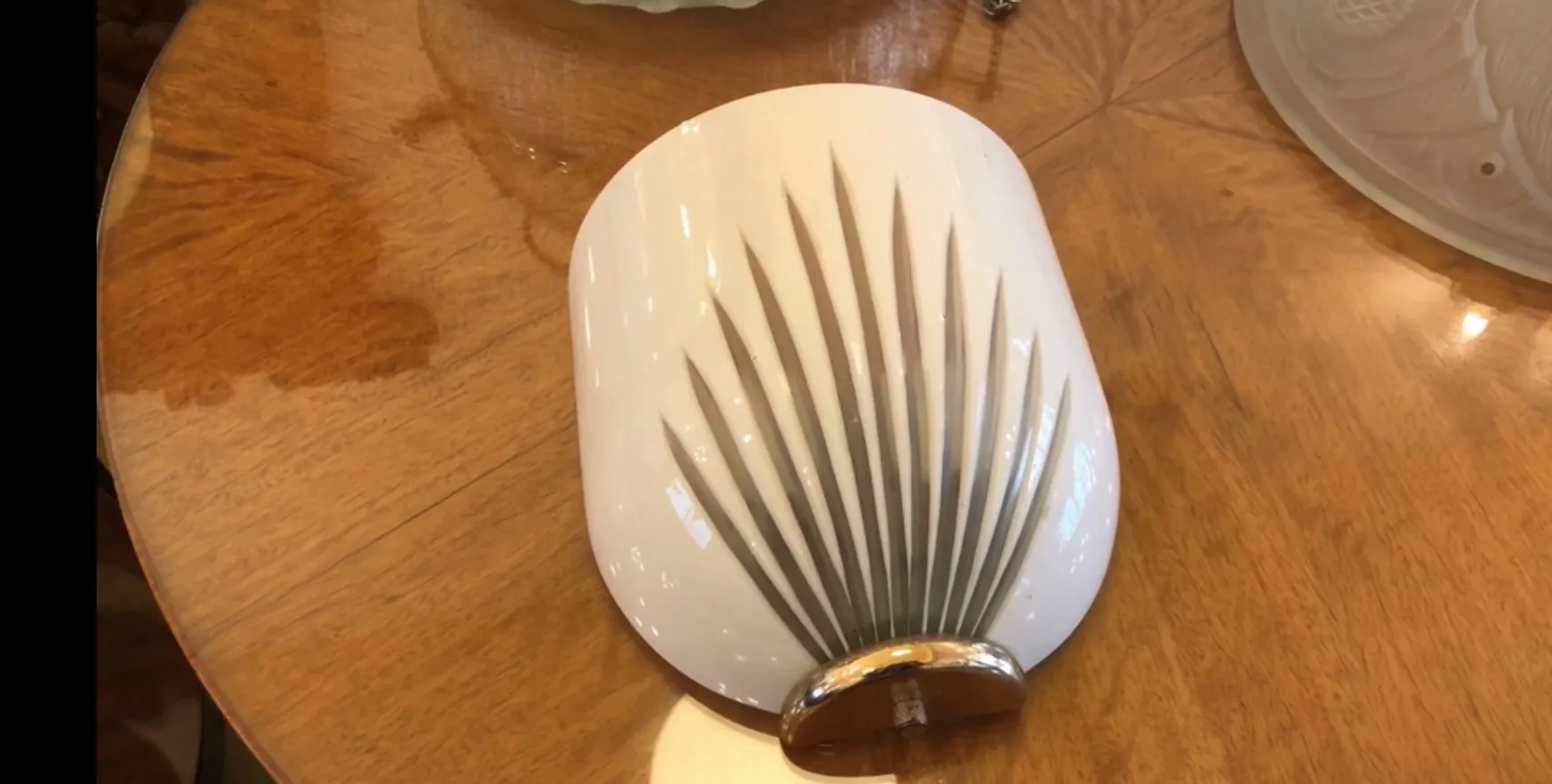 زوج من المصابيح الجدارية القديمة المزخرفة، بيضاء بتصميم بارز، على خلفية من الخشب.