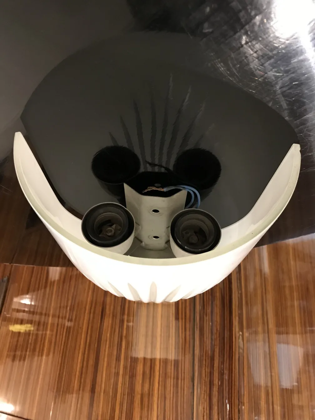 Coppia di applique antiche con forma ovale, colore bianco e componenti elettrici visibili