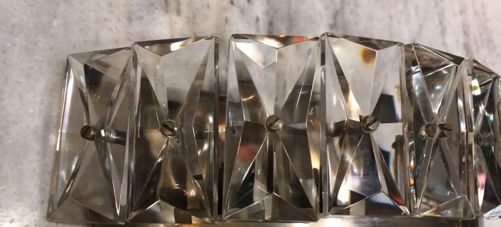 Paar Wandleuchter aus Glas und Metall, beleuchtet vor neutralem Hintergrund