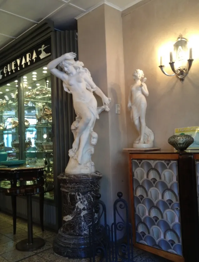 Antike Wandleuchter beleuchten eine Szene mit Statuen.