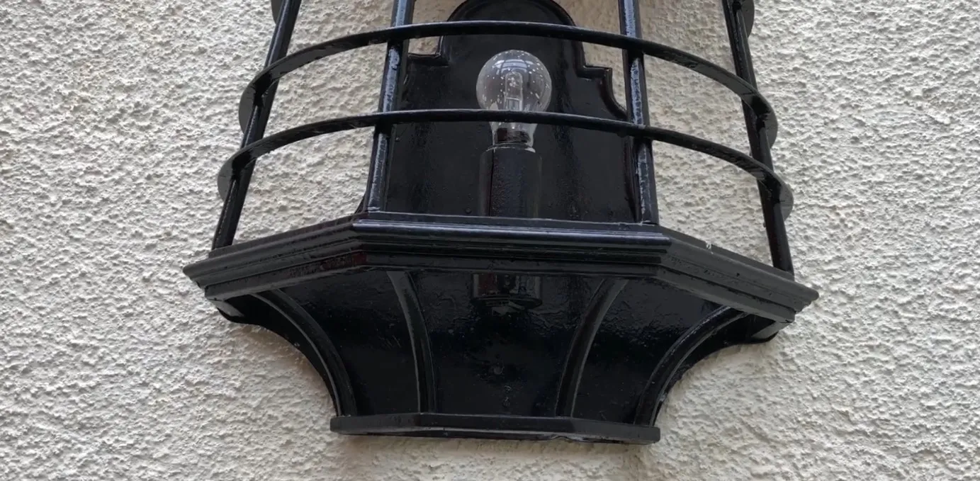 取り付けられた古い黒い壁灯、見える電球、明るい背景。