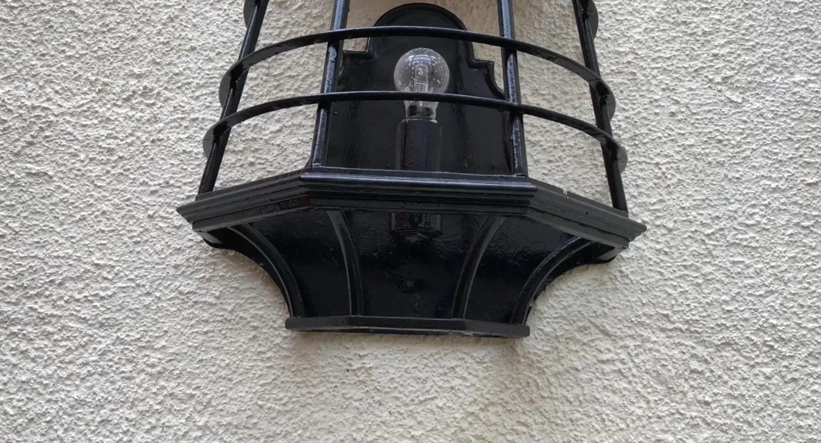 apliques antiguos en forma de farol negro, instalados en una pared clara