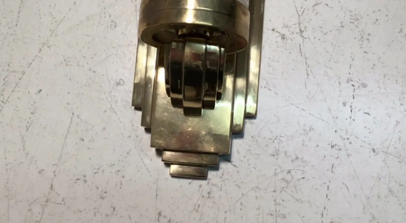 Aplique de pared antiguo con diseño geométrico en tonos dorados, ideal para decorar espacios elegantes.