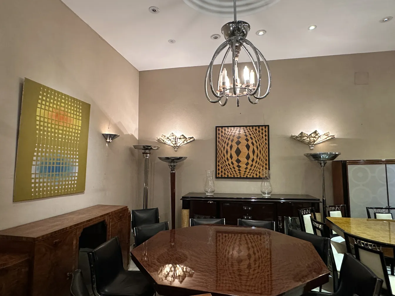 Par de apliques antiguos iluminando una elegante habitación con arte moderno.