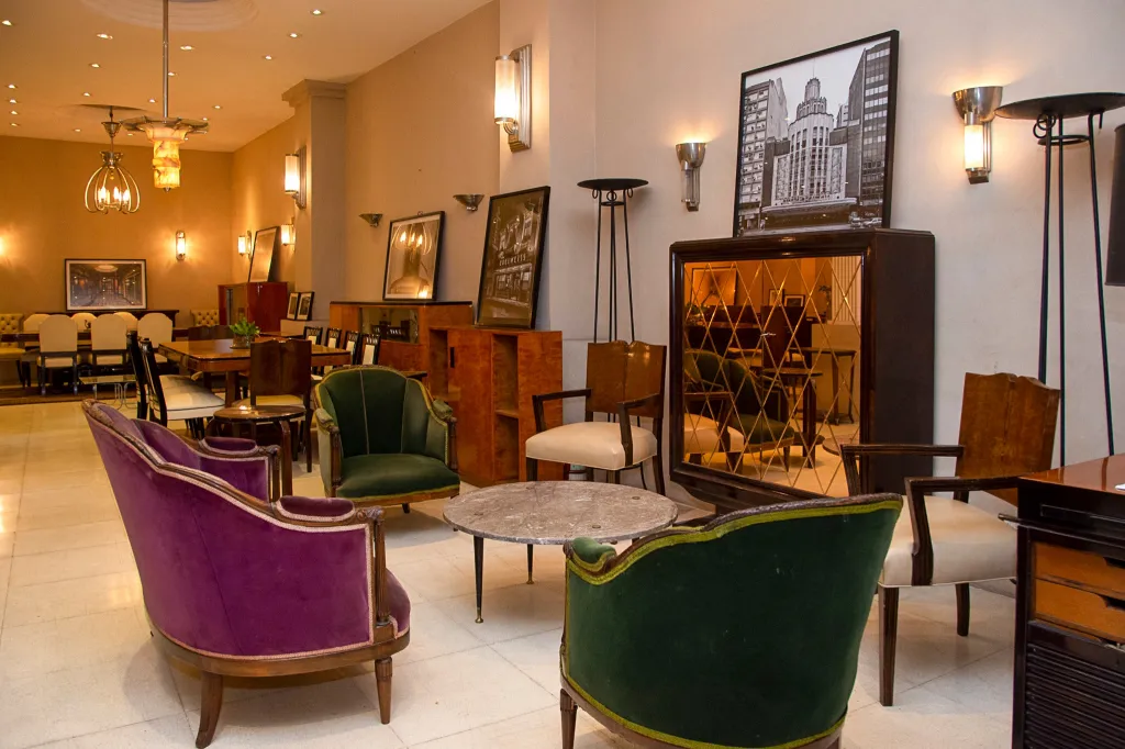 Set antiker Wandleuchter in einem eleganten Ambiente mit Sesseln und klassischer Dekoration.