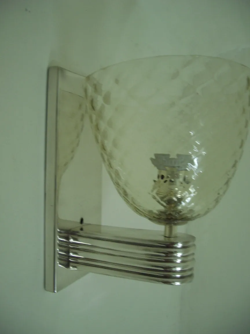 Par de apliques antiguos con diseño en cristal facetado, colocados en una pared blanca.