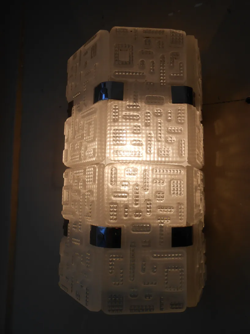 Par de apliques antiguos con diseño geométrico claro, iluminando suavemente la pared.