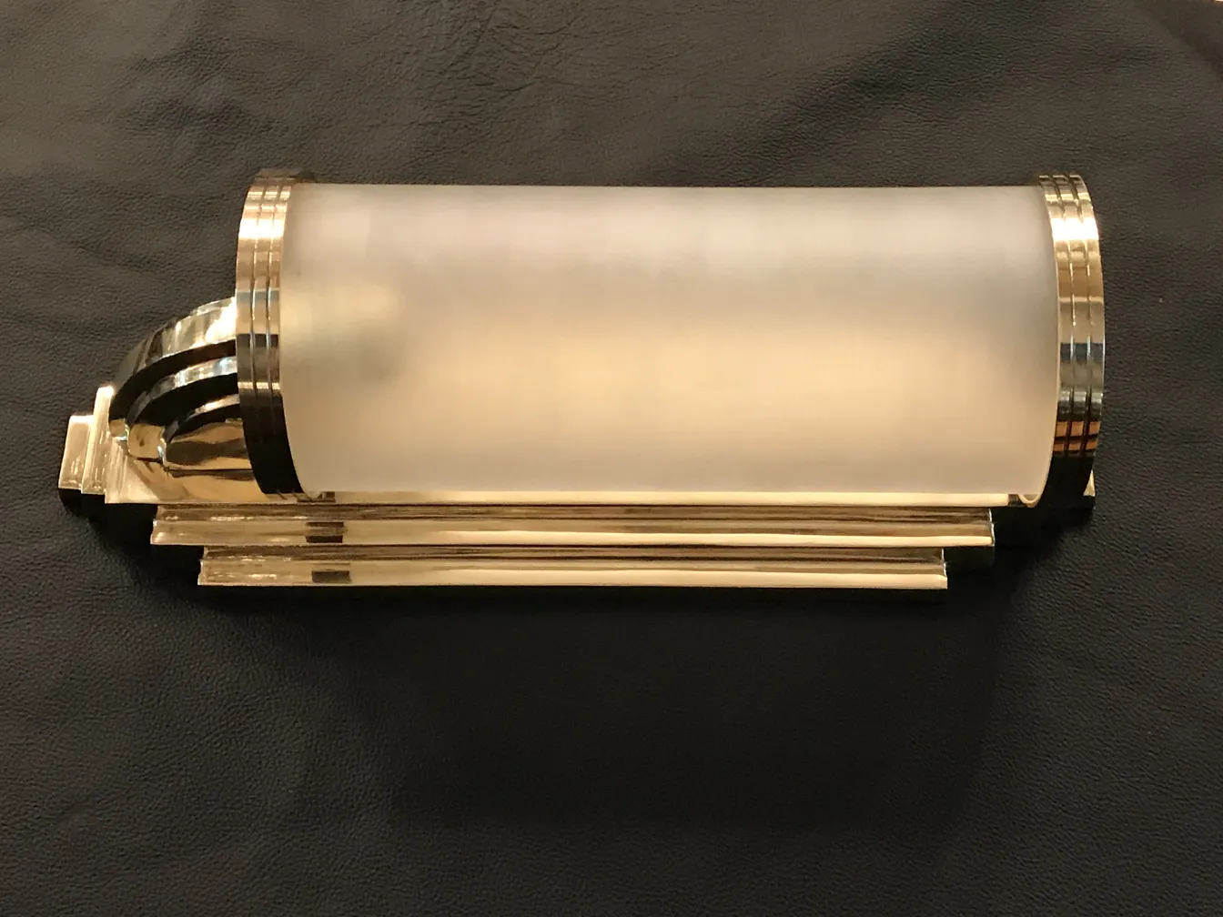 Apliques douradas com vidro fosco, estilo antigo, sobre fundo de couro preto.