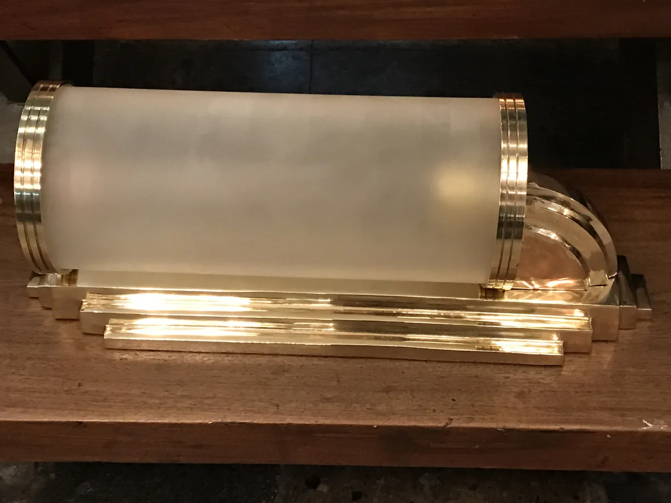 Antikes Paar Wandleuchter mit goldenen Details vor einem Holz-Hintergrund