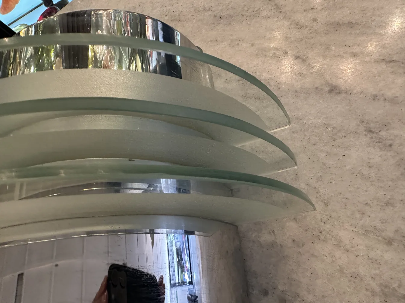 Antiguo par de apliques con diseño curvo y cristal. Se observa un ambiente cálido.