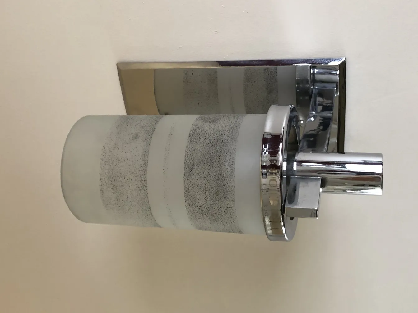 चक्रीय आकार के स्कोनस की जोड़ी, जो हल्की दीवार को रोशन करती है।