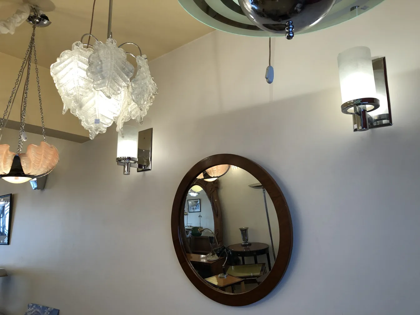 円形の鏡の隣にある古い壁ランプのペア