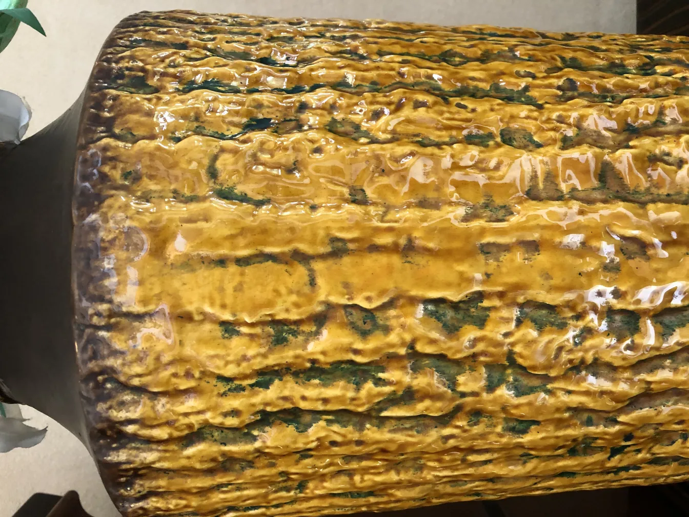 Cerâmica antiga com textura amarela e detalhes verdes.