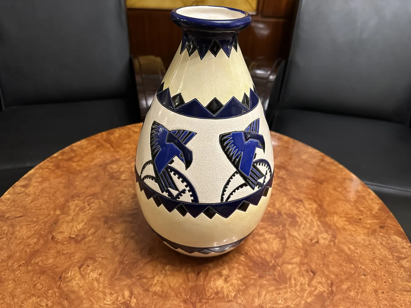 Jarrón de ceramica antigua decorado con pájaros azules sobre fondo claro.