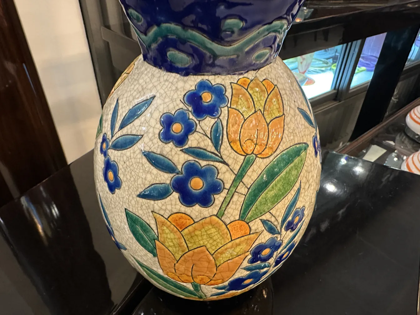 Vaso de cerâmica antiga com design floral e folhagem em cores vibrantes.