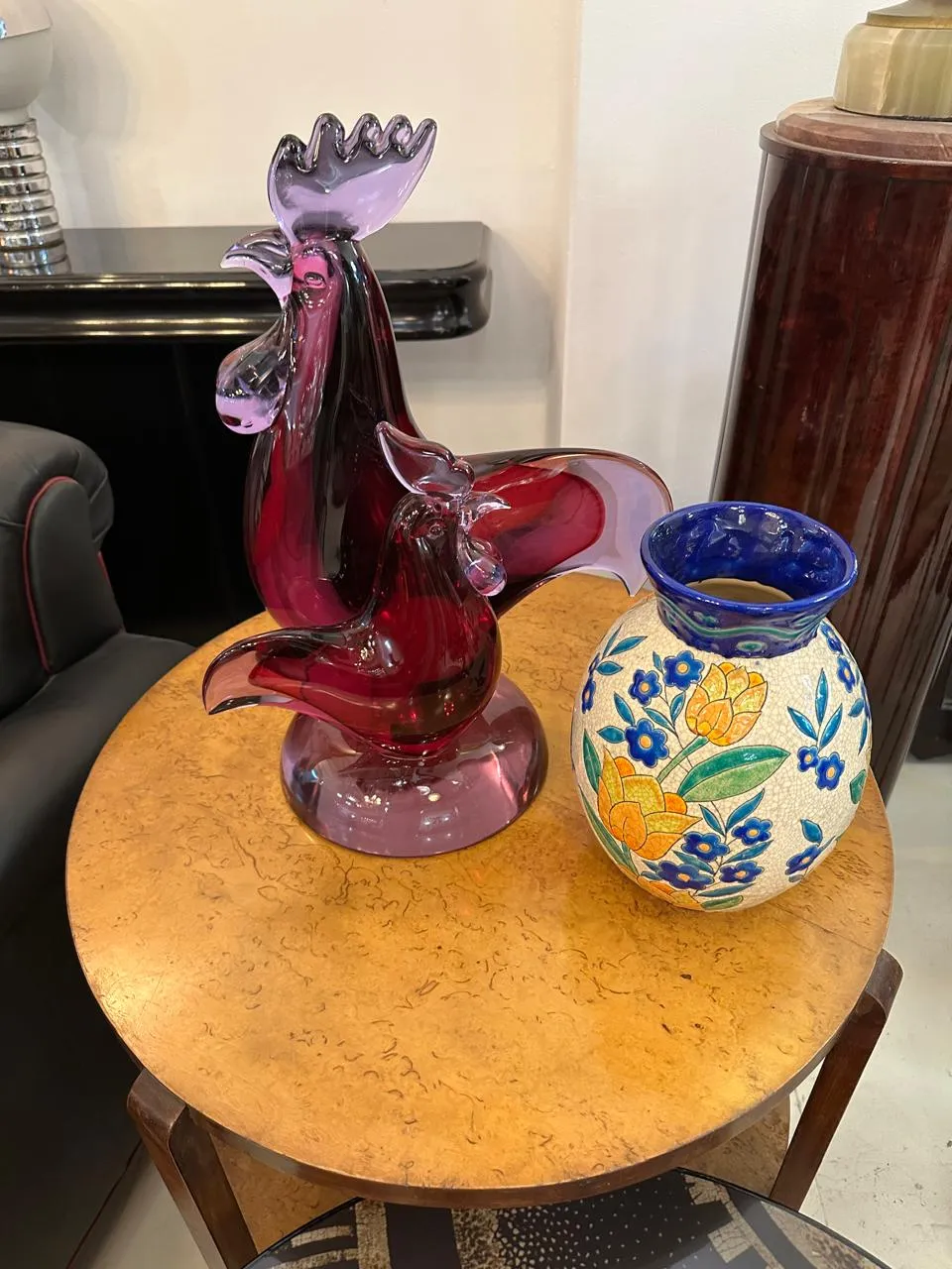 Vaso de cerâmica antiga decorado com flores e um galo de vidro colorido na mesa