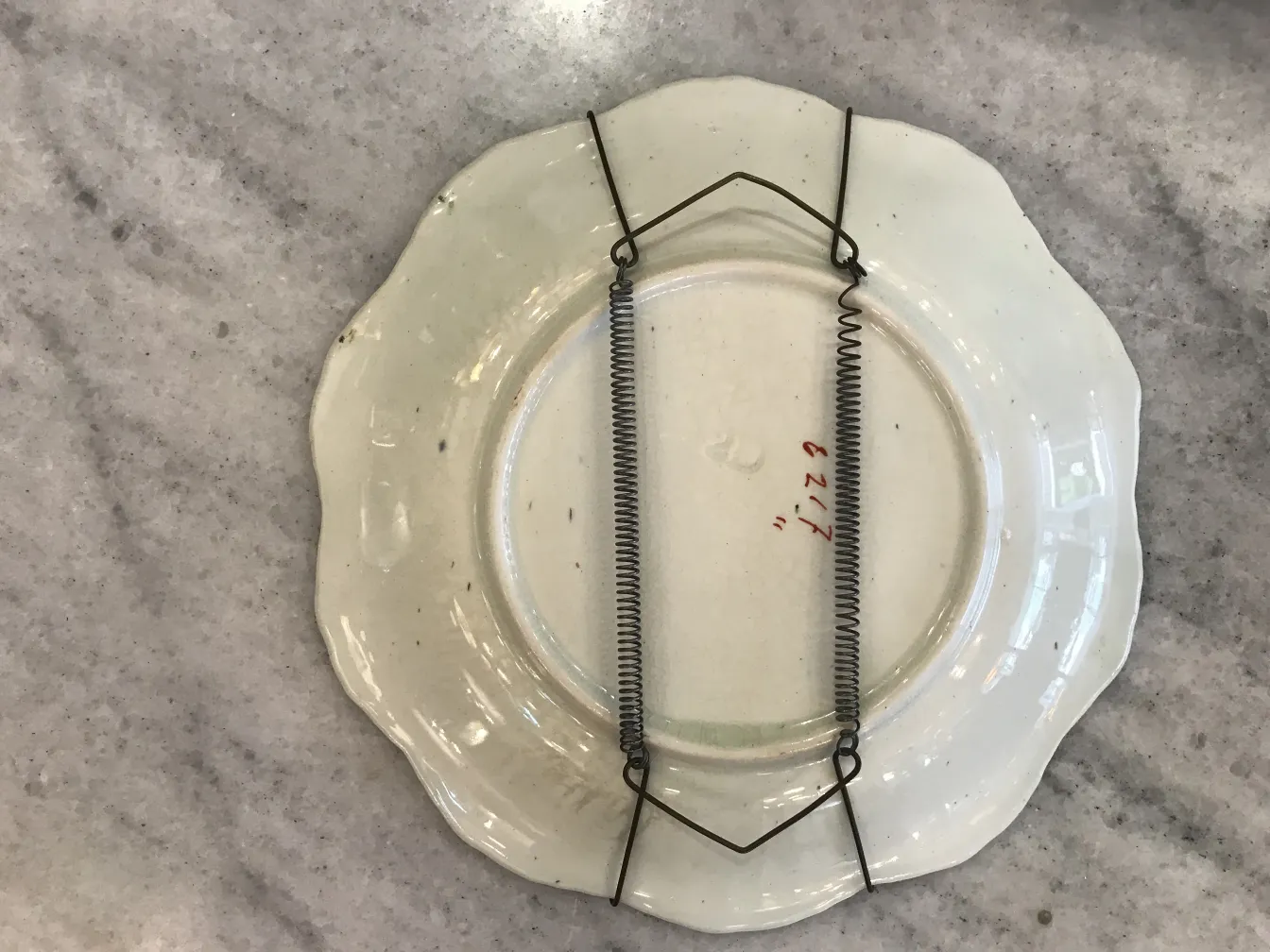 金属サポート付きの古い白い陶器の皿、下から見た。