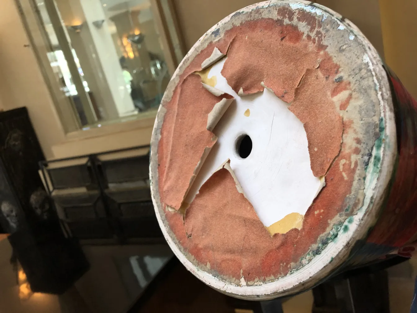 View of the base of an antique glazed ceramic with colorful patterns and worn details.