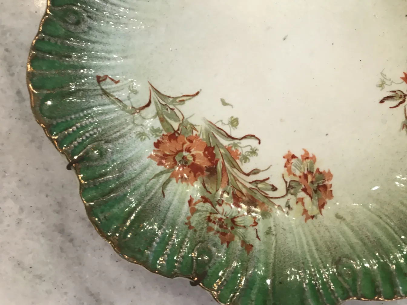 Plato antiguo de cerámica con decoración floral y verde.