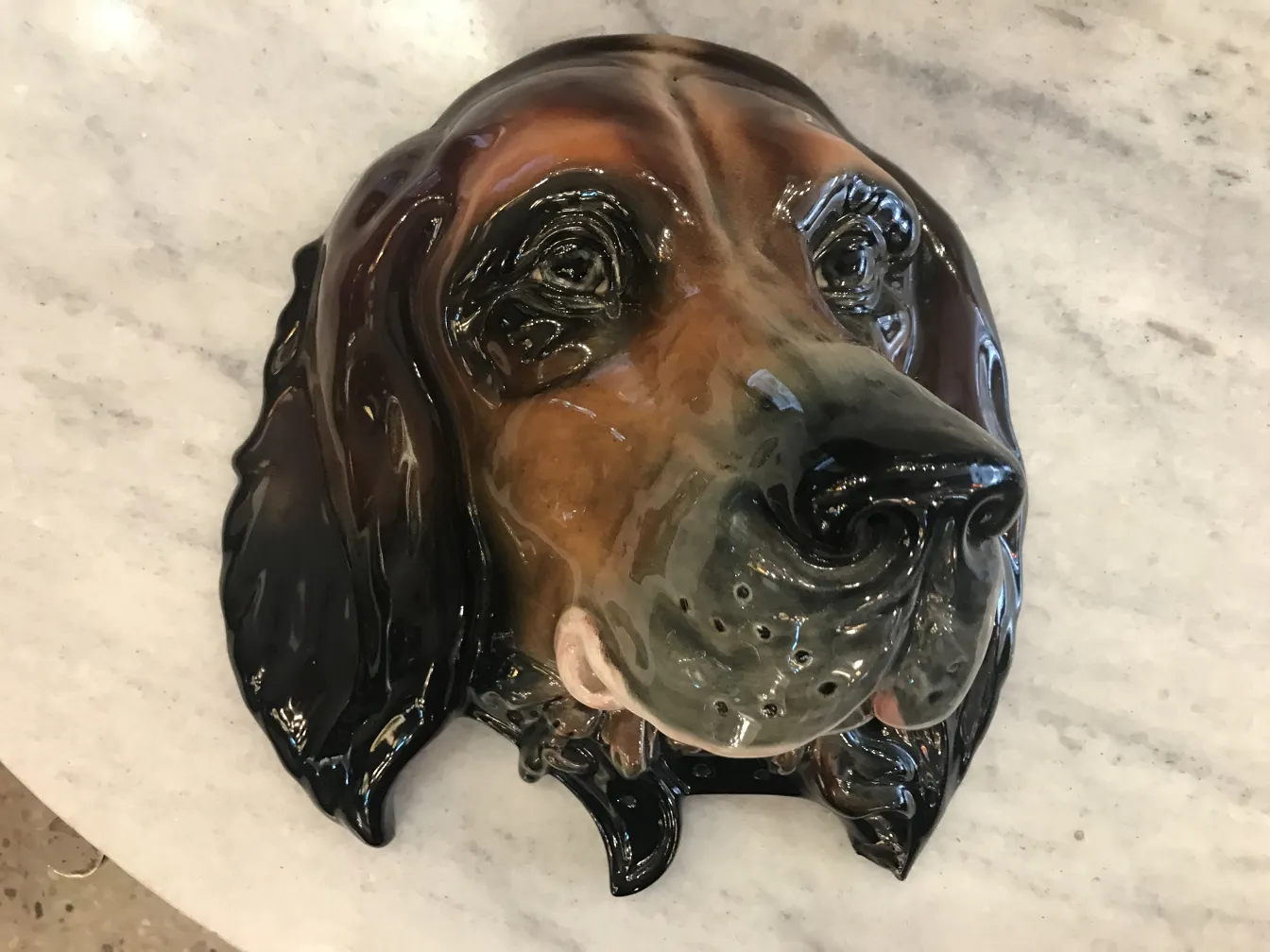 Antique ceramic relief featuring a glossy dog head.