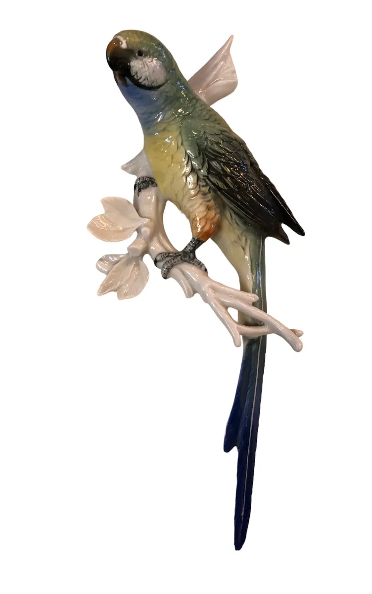 Figura cerâmica antiga de um pássaro com detalhes coloridos em um galho