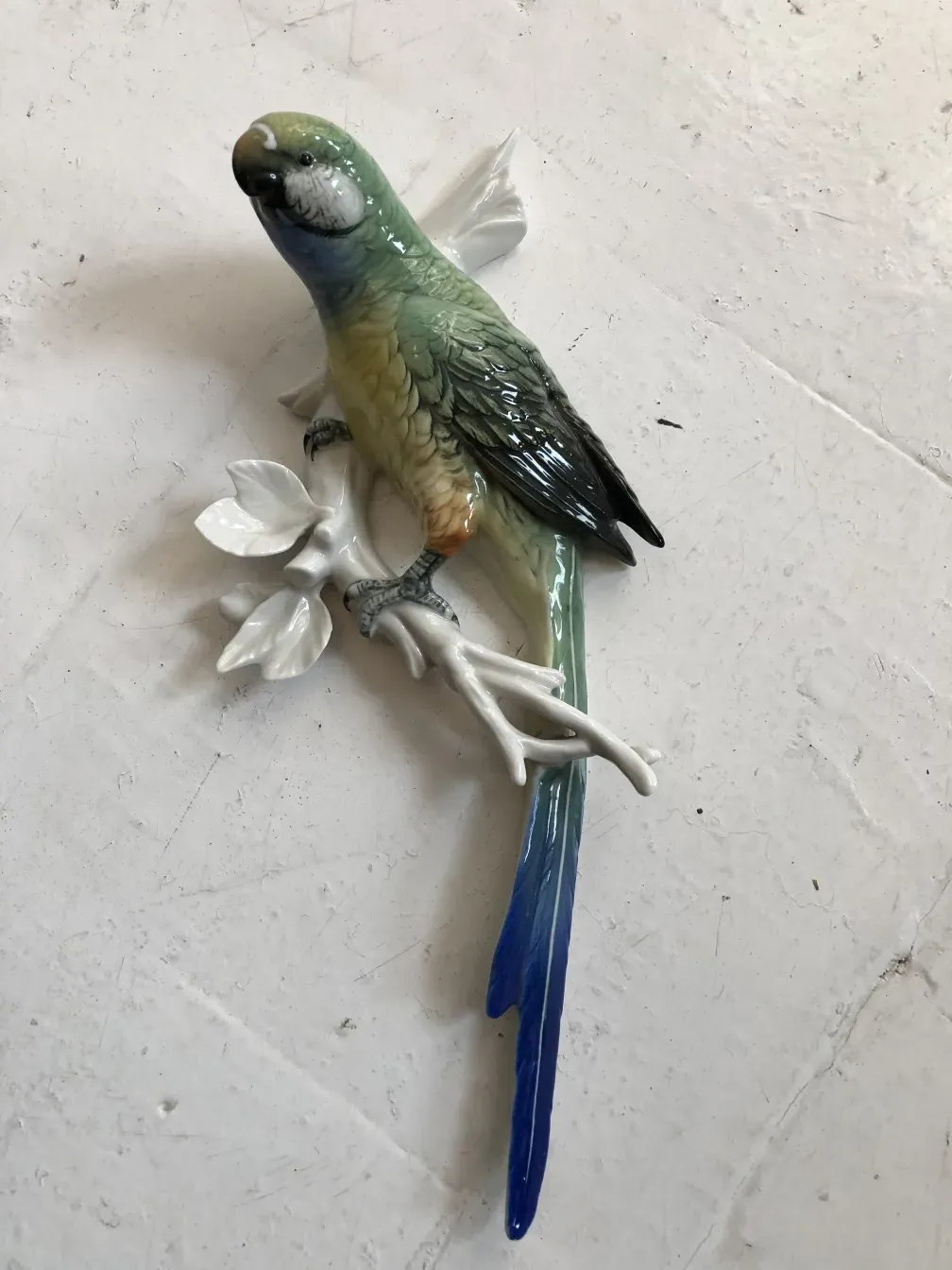Escultura antigua de cerámica de un pájaro en una rama.