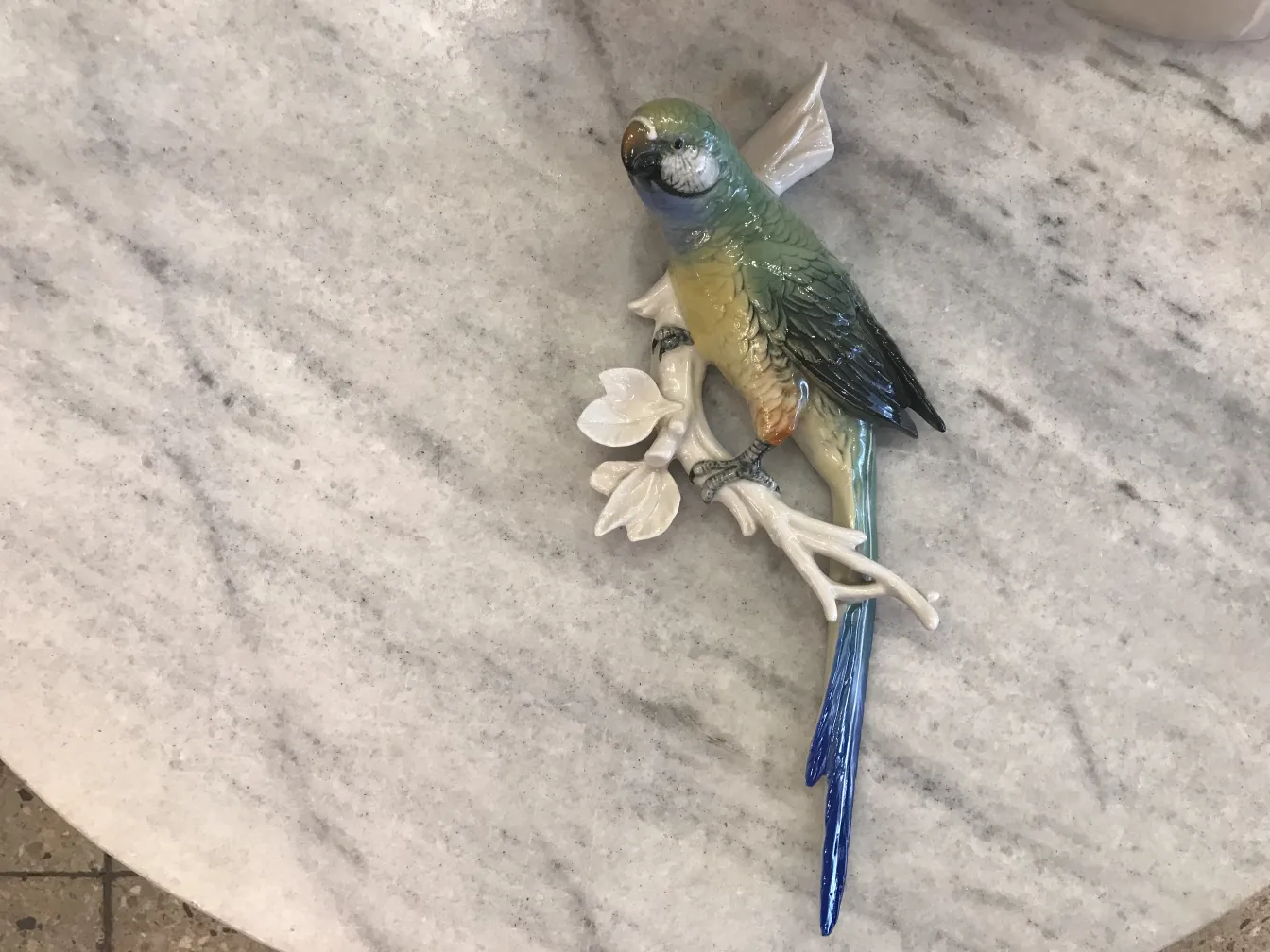 Statue en céramique ancienne d'un oiseau perché sur une branche avec des fleurs