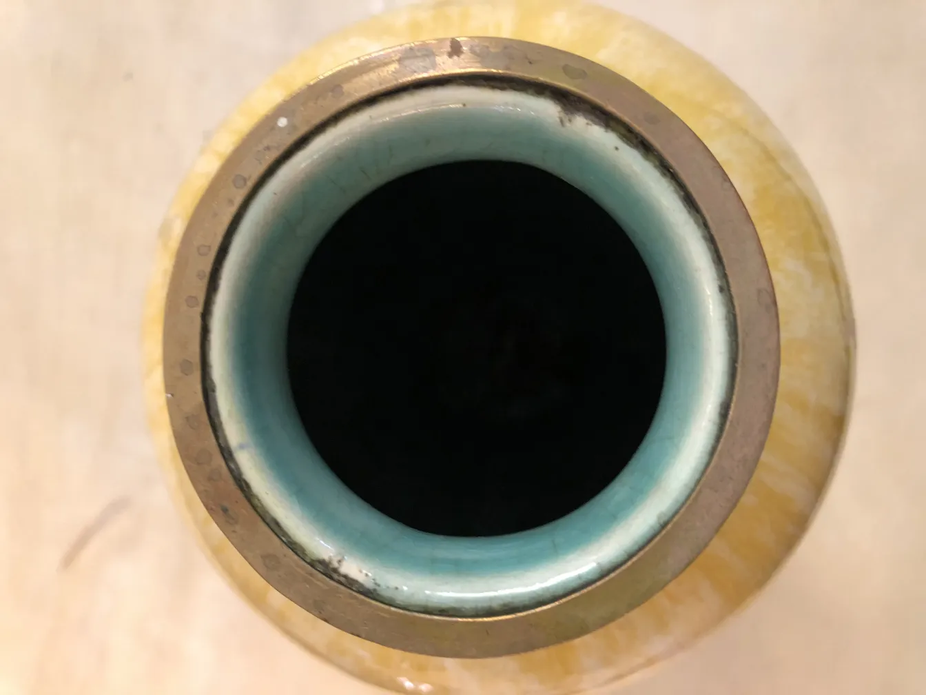 古い黄色の陶器の花瓶の内部、青い縁があります。