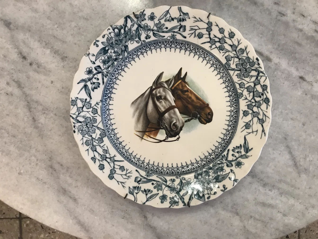 Placa de cerâmica antiga com imagem de cavalos e borda floral