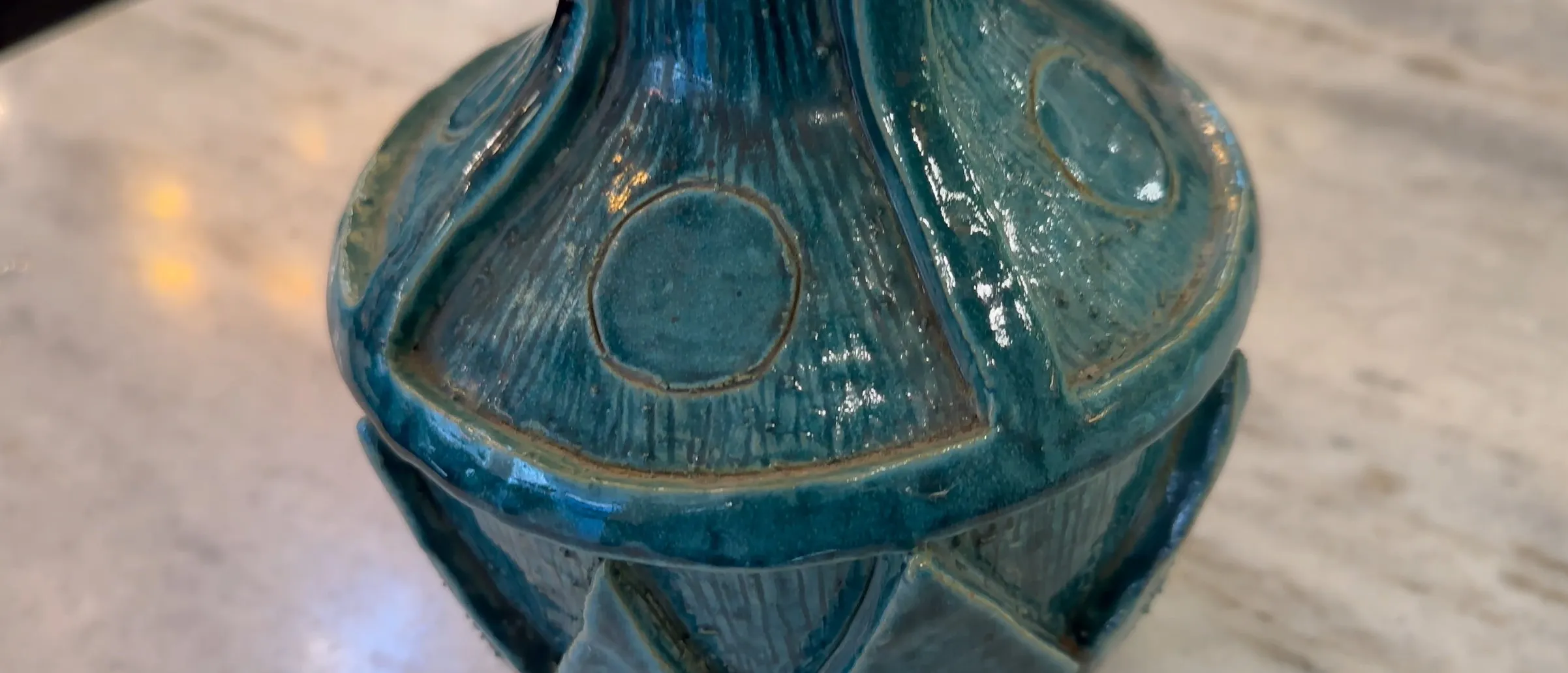 Ceramica antica con dettagli blu e texture distintiva in un ambiente elegante.