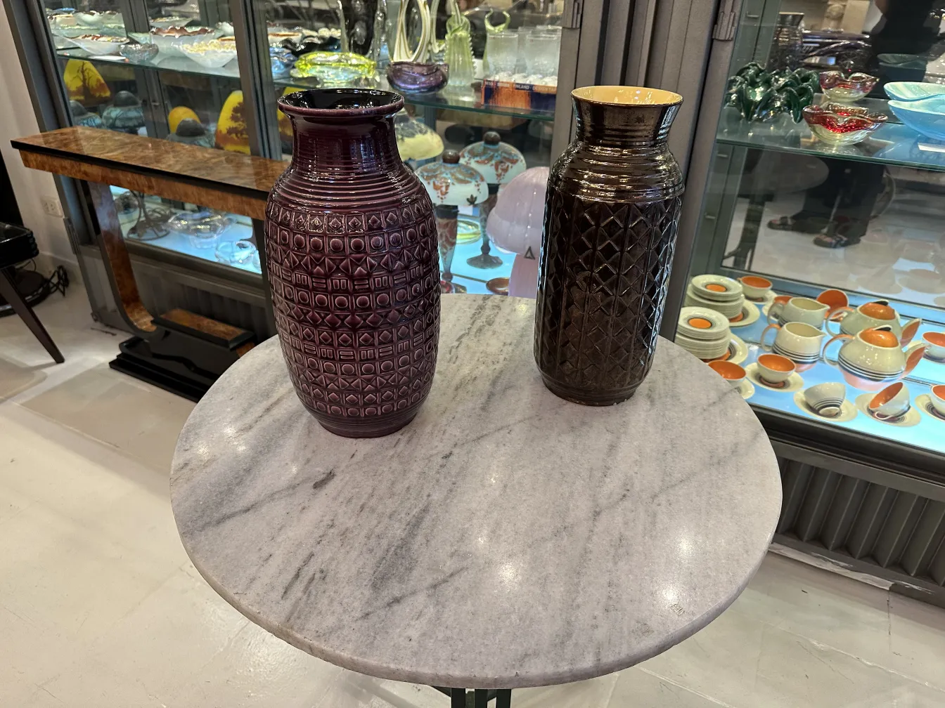 Dois vasos cerâmicos antigos em uma mesa de mármore, fundo decorativo.