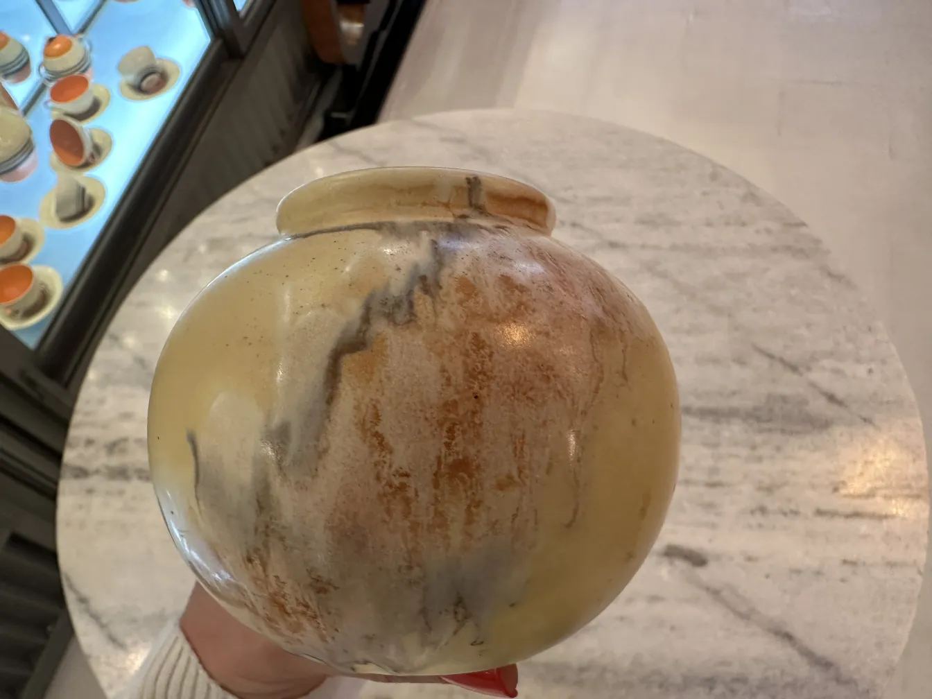 Vaso de cerâmica antiga com cores quentes e superfície texturizada, em um ambiente bem iluminado