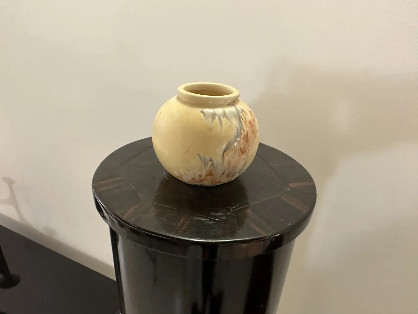 古董陶瓷花瓶，涂有黄色和棕色，放置在黑色表面上。