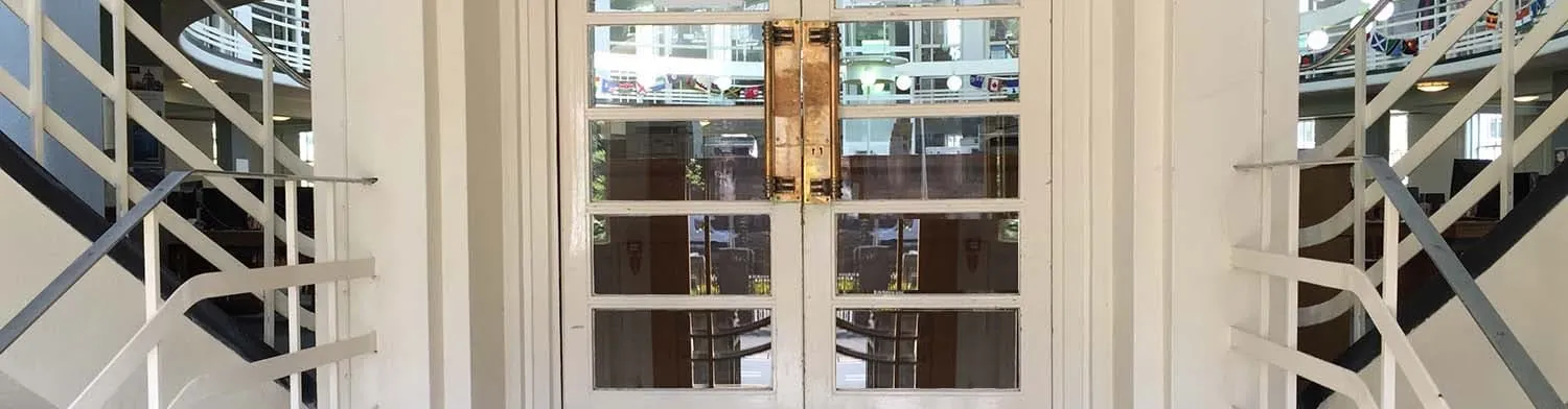Elegante puerta de vidrio con tiradores dorados, rodeada por un entorno moderno.