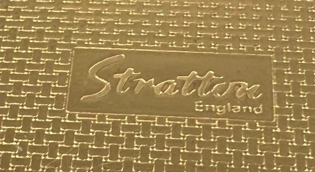 sello antiguo con marca Stratton England en fondo dorado